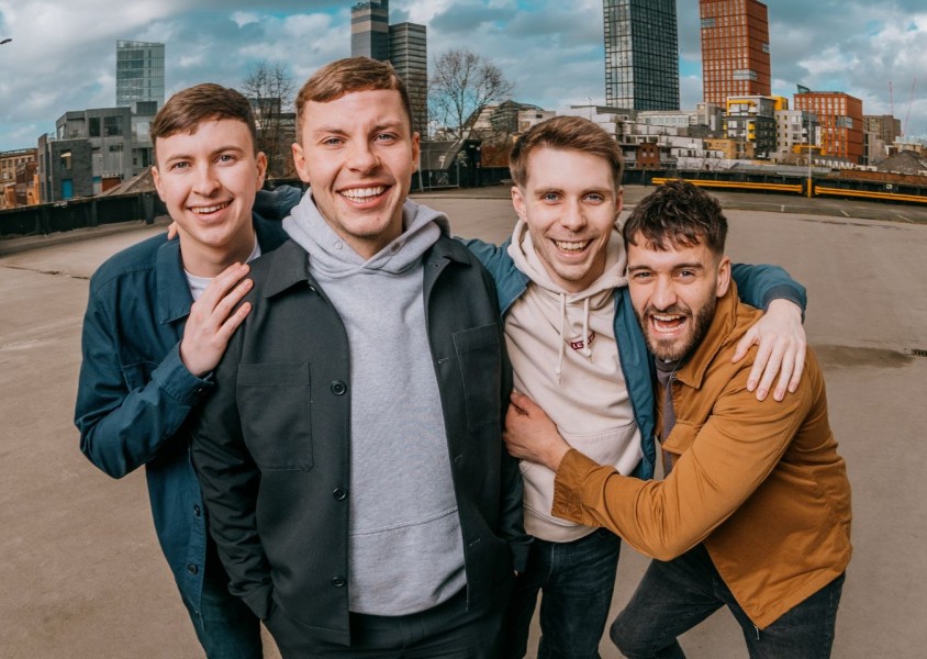 Four members of The Lilacs stood in an empty car park with high rise flats in the backgroundx